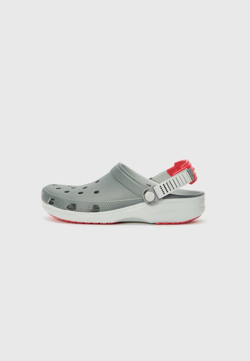 Grauer Clogslipper aus leichtem Material, mit Belüftungslöchern, verstellbarem Fersenriemen und einem roten Akzent an der Rückseite.