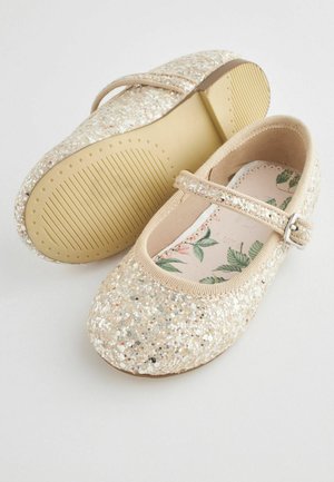 Glitrende beige ballet flats med en rem, der har en tekstureret sål og en indersål med blomsterdesign. Den funklende finish tilføjer visuel interesse.