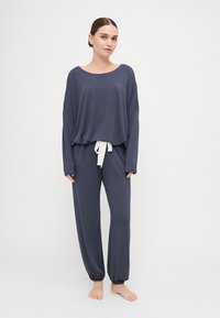 Navy lounge set with a loose, long-sleeve top and elastic waistband pants, featuring a white drawstring and tapered cuffs for comfort.