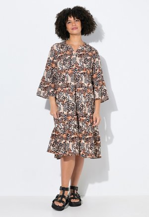 Bloemenprint dierenprint jurk in bruin, oranje en zwart met een knoopsluiting aan de voorkant, uitlopende mouwen en een gerimpelde zoom. G gedragen met zwarte sandalen.