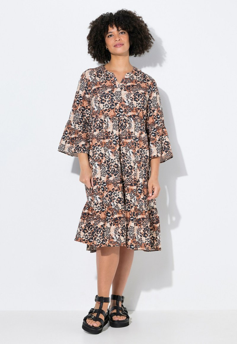Bloemenprint dierenprint jurk in bruin, oranje en zwart met een knoopsluiting aan de voorkant, uitlopende mouwen en een gerimpelde zoom. G gedragen met zwarte sandalen.