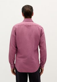 Cămașă cu mânecă lungă din material texturat, solid, de culoare magenta. Are guler în formă de vârf, manșete cu nasturi și o margine curbată.