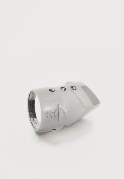 Δαχτυλίδι από ασημί σε τμήματα με τρεις πριτσίνους και χαραγμένο έμβλημα σε ομαλή λευκή επιφάνεια.