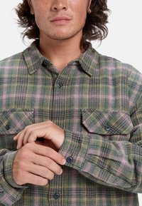 Grün-lila-gelb kariertes Flanellhemd mit langen Ärmeln, geknöpften Manschetten und zwei Brusttaschen. Hat ein klassisches Kragendesign.