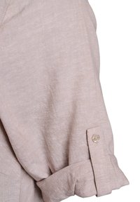 Tessuto di camicia in lino beige con risvolto, caratterizzato da un singolo bottone al polsino e una superficie liscia e texture.