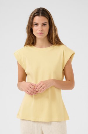 Haut jaune à manches courtes avec une coupe décontractée et un col arrondi. Le tissu semble doux, avec une texture lisse et des détails de couture minimaux.