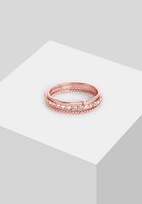 Anello in oro rosa con design a spirale, decorato con pietre trasparenti lungo la parte superiore. Finitura liscia con una texture lucida.