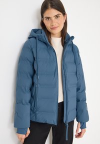 Blå puffy jakke med hætte, lynlåslukning foran, elastiske manchetter og sidelommer. Har et kviltet design og blød tekstur.