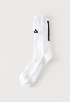 Calzino sportivo bianco con striscia nera e logo nero, trama a coste e suola imbottita su uno sfondo chiaro e uniforme.