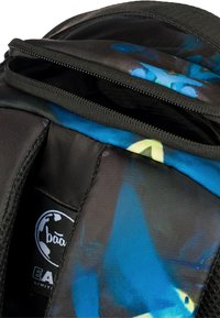 Zaino con tessuto nero e motivi astratti colorati blu e gialli; presenta un'apertura con zip e un'etichetta di marca all'interno.