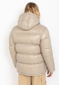 Beige gewatteerde jas met een capuchon, met een glanzende textuur, horizontale naden en een snug fit rond de taille en schouders.