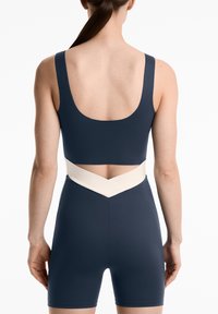 Navy blue athletic bodysuit with a wide square back, white v-shaped waistband, and smooth texture. Features short legs for mobility.