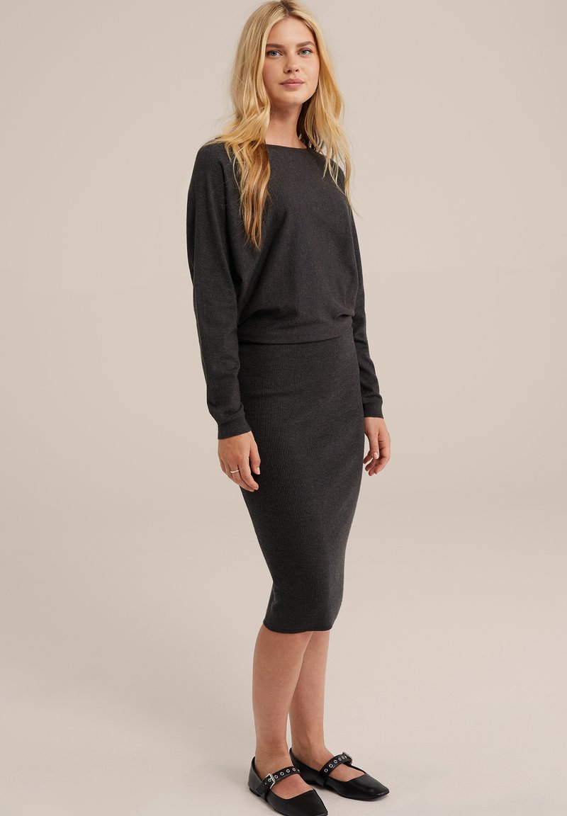 Ciemnoszary sweter z dzianiny i spódnica ołówkowa, charakteryzujące się luźnym krojem, prążkowaną teksturą i czarnymi płaskimi butami na paski.