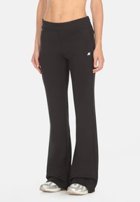 Pantaloni tuta neri a svasare realizzati in tessuto morbido con una consistenza liscia, con un logo discreto sulla vita e tasche laterali.