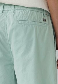 Helle grüne Shorts aus weichem Material mit einer strukturierten Oberfläche; verfügen über eine Gesäßtasche und ein kleines Logotag in der Nähe des Bundes.