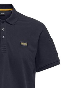 Dunkelblaues Polohemd, kurze Ärmel, Knopfleiste mit drei Knöpfen, gelber Akzent am Kragen, strukturiertes Gewebe, Aufnäher-Logo auf der Brust.