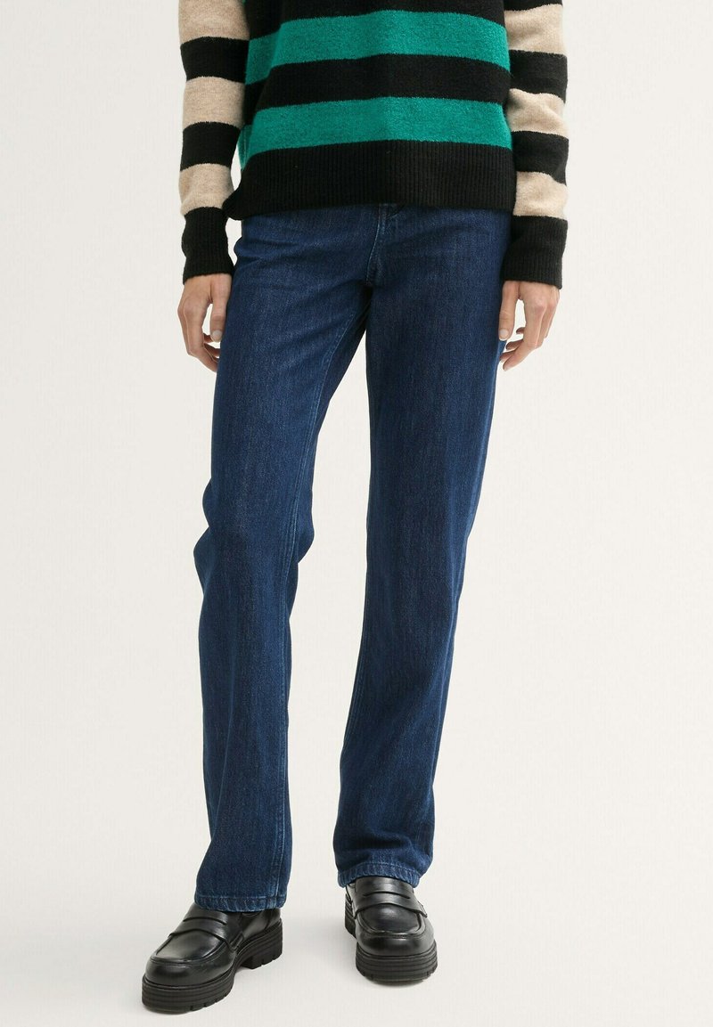 Blå denim jeans med lige snit, parret med en sorte og grøn stribet sweater og chunky sorte loafers.