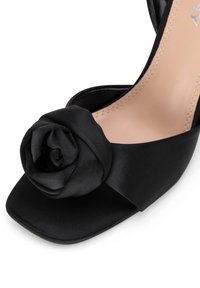 Czarne satynowe szpilki z kwadratowym czubkiem i dużą różą na cholewce. Gładka tekstura i elegancki design.