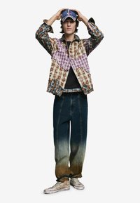 Barna, kék és lila foltvarrásos ing kockás mintával. Sötétkék átmenetes farmernadrággal és mintás tornacipővel párosítva.