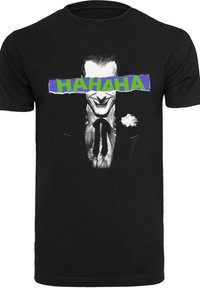 Melnas kokvilnas t-krekls ar grafiku, kurā attēlots smaidīgs varonis uzvalkā, ar drosmīgu tekstu "HAHAHA" pāri sejai zaļā un zilā krāsā.