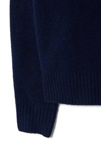 Dunkelblauer Strickpullover mit weichem, strukturiertem Finish. Verfügt über gerippte Bündchen und Saum, die eine figurbetonte Silhouette schaffen.