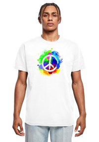 Hvid bomulds t-shirt med et farverigt fredssymbol design, der har sprøjt af grøn, blå, rød og gul i et malerisk splatter stil.