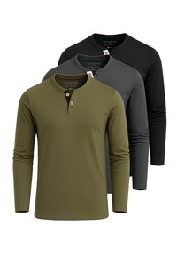 Tres camisas de manga larga en verde oliva, gris oscuro y negro; cuello redondo, detalle de botones en el collar, textura de tela suave.