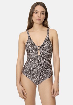 Mujer con un bañador de una pieza con un patrón abstracto en negro y beige y un detalle de anillo delantero en un corte tipo ojo de cerradura.