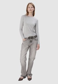 Szara koszula z długim rękawem w połączeniu z jasnoszarymi dżinsami. Czarno ozdobny pasek i czółenka w zwierzęcy wzór dopełniają strój.