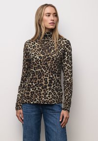 Pull à col roulé manches longues à imprimé léopard, avec une base beige et des taches noires et brunes, texture lisse et coupe ajustée.