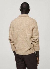 Beige pletený svetr s texturovaným povrchem, s překládaným límcem a žebrovaným lemem, zobrazený zezadu na modelce.