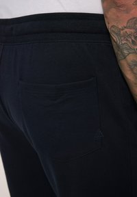 Navy Jogginghosen aus weichem Material, mit gestepptem Gesäßtasche und einem gerippten Bund für einen sicheren Sitz. Detailliertes Dreieckslogo abgebildet.
