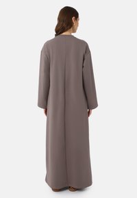 Vêtement long, gris uni avec une coupe décontractée, encolure ronde, manches longues et texture lisse, tombant jusqu'aux chevilles.