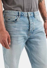 Jeans in denim blu chiaro con una vestibilità slim, dotati di tasche anteriori e posteriori, e una discreta etichetta sul taschino posteriore. Texture liscia.