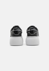 Schwarze Lackledersneaker mit einer weißen gerippten Sohle. Mit einem Logo auf der Rückseite und einem Reißverschluss an der Seite. Abgerundete Zehenform.