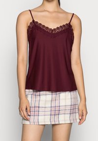 Bordeaux kleurige top met kantafwerking, aangevuld met een geruite minirok in crème, paars en blauw. Gladde stofstructuur door het geheel.