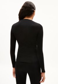 Schwarzes, geripptes Langarmoberteil mit rundem Halsausschnitt und figurbetontem Design, aus dehnbarem Stoff für eine enge Passform.