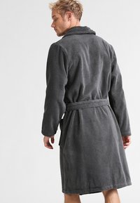 Dunkelgrauer Fleece-Bademantel mit langen Ärmeln, einem Schalkragen und einem gebundenen Taillengürtel. Weiche Textur mit glatter Oberfläche.