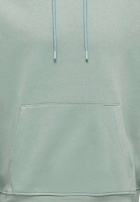 Sudadera verde menta clara hecha de una tela suave, con un bolsillo tipo canguro, cordones y puños acanalados de textura suave.