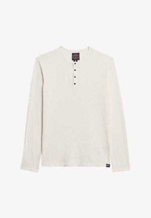 Long-sleeve henley shirt in cream with a textured fabric, featuring a round neckline and five black buttons on the front.