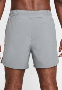 Grå simshorts med elastisk midja, slät textur och bakficka, designade för komfort och rörlighet.