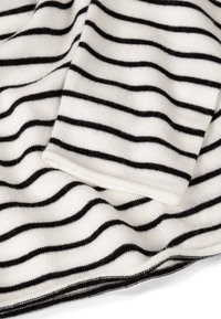 Tela a rayas en blanco y negro, con una textura suave y una manga holgada. Las rayas están espaciadas uniformemente, con un dobladillo limpio.