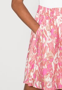 Hame floral print, joka sisältää vaaleanpunaisia ja valkoisia värejä, joustavan vyötärön ja sivutaskut. Pehmeä kangas, jossa on virtaava muotoilu ja hillitty kiilto.