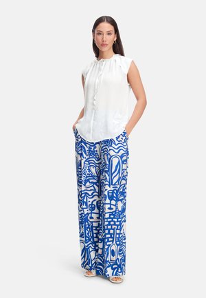 White sleeveless blouse with ruffled neckline, paired with blue and white patterned wide-leg pants featuring abstract designs.