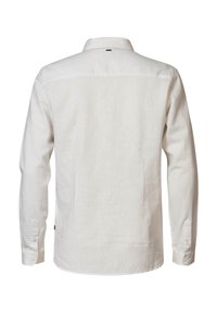 Vue de dos d'une chemise en lin beige clair à manches longues avec poignets boutonnés et une petite étiquette noire près du col.