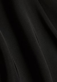 Tissu noir lisse avec des plis diagonaux subtils et une texture mate douce.