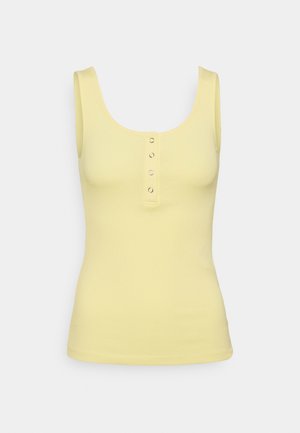 Keltainen urheilullinen toppi, jossa on kapea kaula-aukko ja viisi metallista nappia edessä. Kangas on sileä ja tiukka.