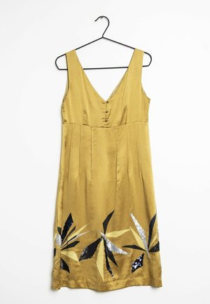 Vestito giallo senza maniche con profondo scollo a V, dettagli con bottoni sul petto e motivi di foglie nere, crema e argento con paillettes vicino all'orlo.