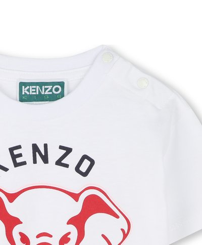 T-shirt en coton blanc avec un graphique d'éléphant rouge et le texte "KENZO" en noir. Comprend des boutons-pression à l'épaule pour un enfilage facile.