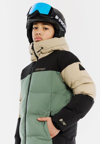 Gepolsterte Skijacke in Grün, Schwarz und Beige, mit Reißverschluss vorne, verstellbarem Kapuzen und Logo-Details. Verfügt über seitliche Taschen zur Aufbewahrung.